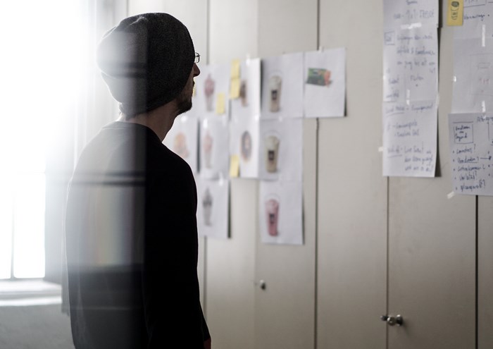 Man in beanie looking at design sketches on wall