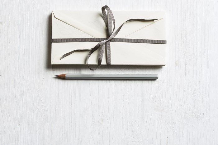 Envelope with ribbon and pencil on white desk