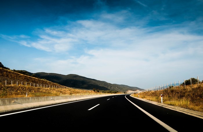 Highway road curving through mountains under a blue sky