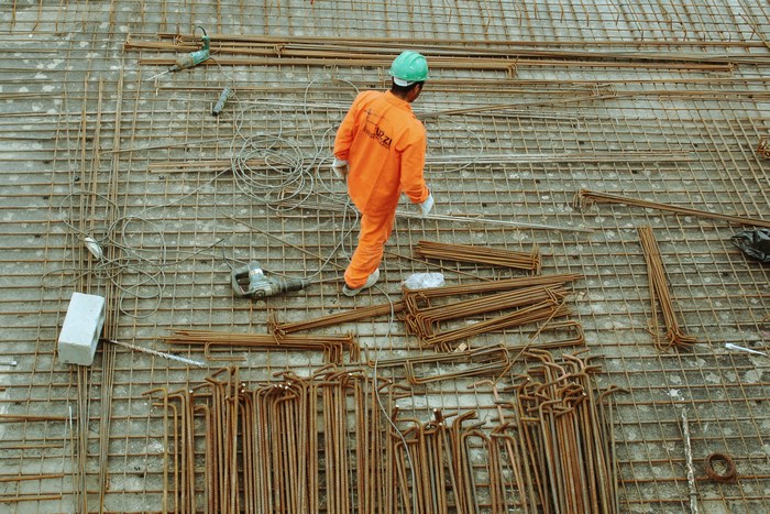 Construction worker in orange uniform on steel rebar grid in Sao Paulo