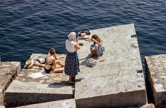 People sunbathing on a concrete pier by the sea
