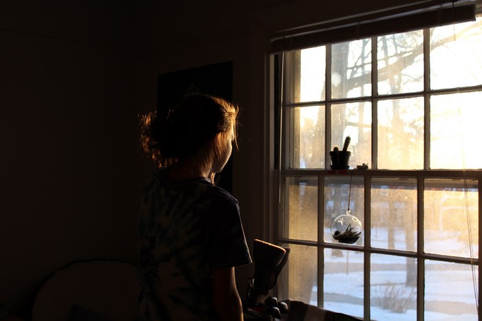 Woman looking out a window at sunrise