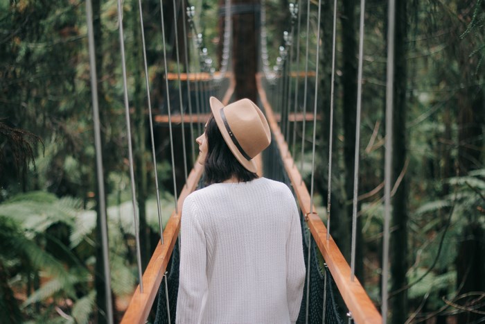 Woman on suspension bridge in forest