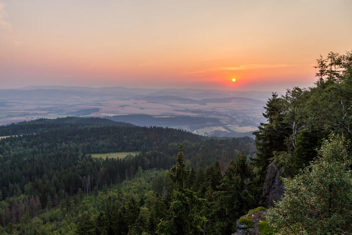 Sunset over a forested valley with distant hills
