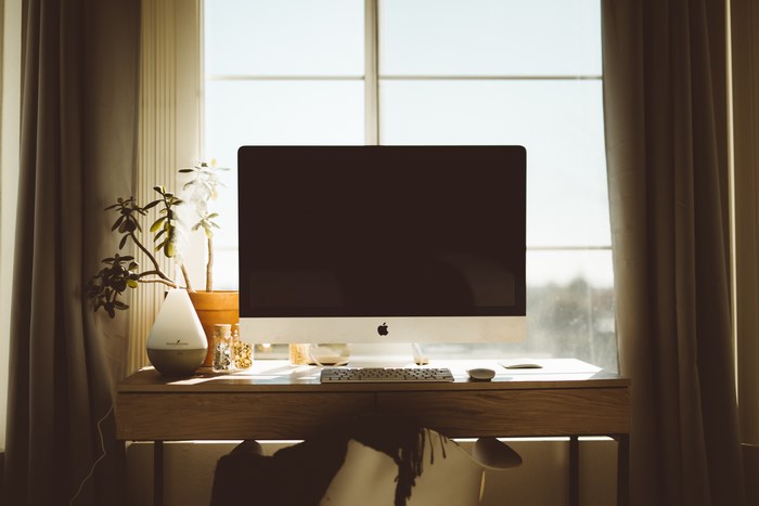 Desk with iMac computer and plants by window