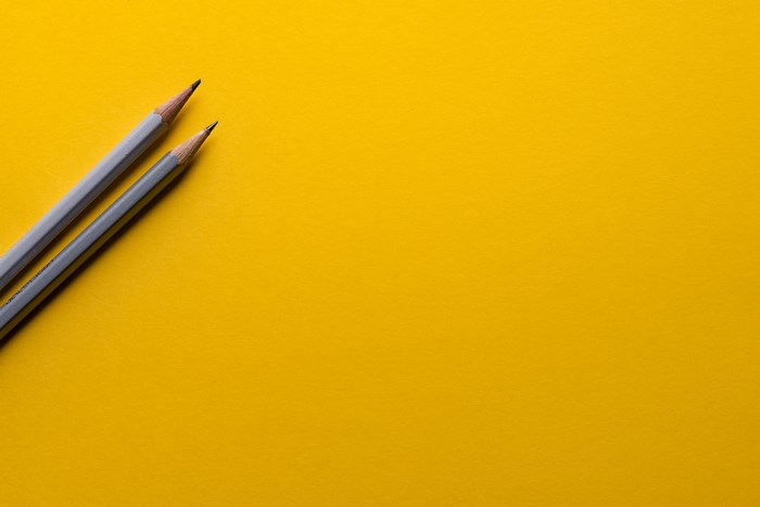 Two sharpened pencils on a yellow background