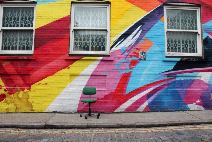 Green chair in front of colorful street art mural