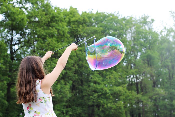 Girl blowing a large rainbow bubble