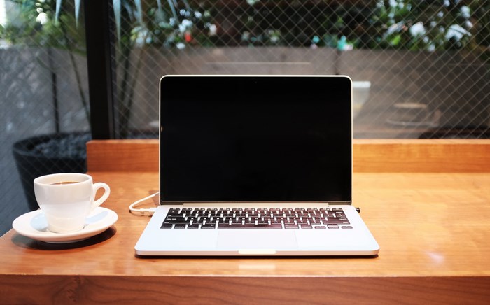 Laptop and Coffee Cup on Wooden Desk by Window