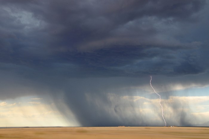 Lightning strikes during a thunderstorm over a desert landscape