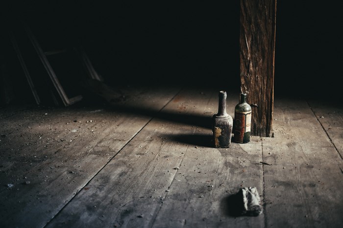 Two old bottles on a dusty wooden floor