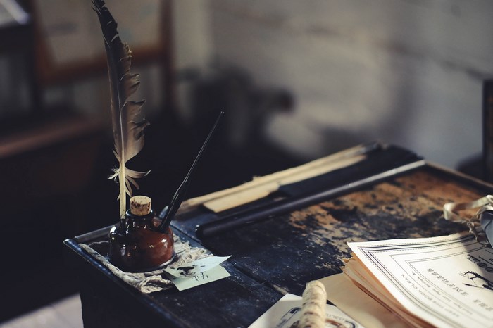 Old desk with quill, inkwell, and papers