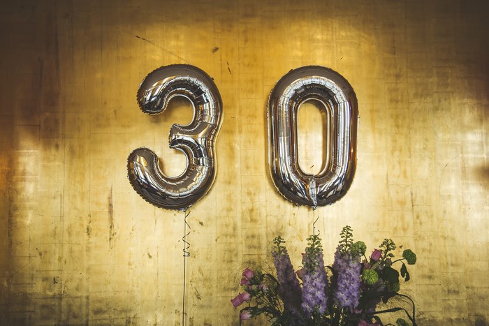 Silver 30 balloons on a gold textured wall