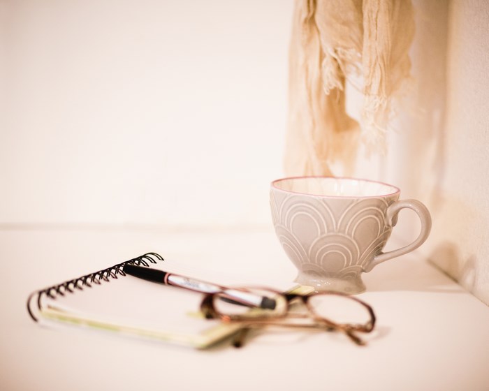 Notebook, pen, glasses, and mug on a desk