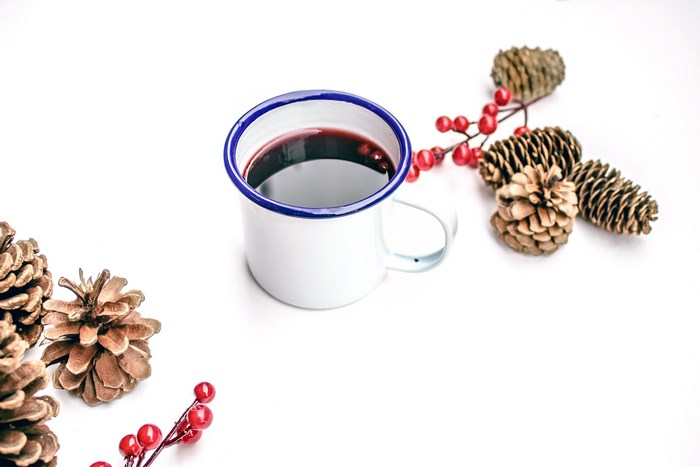 White mug with mulled wine and pine cones