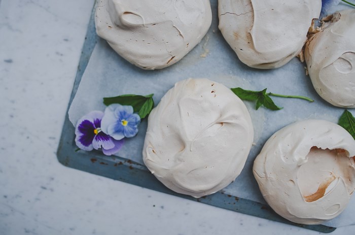 Pavlova meringues with viola flowers on a baking tray