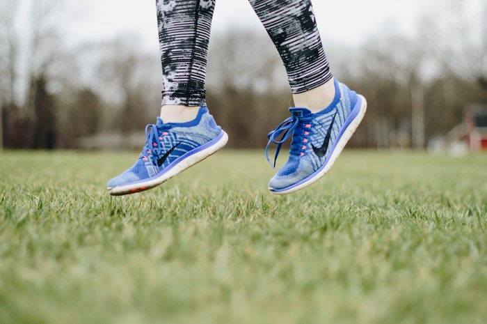 Nike running shoes on a person jumping on grass