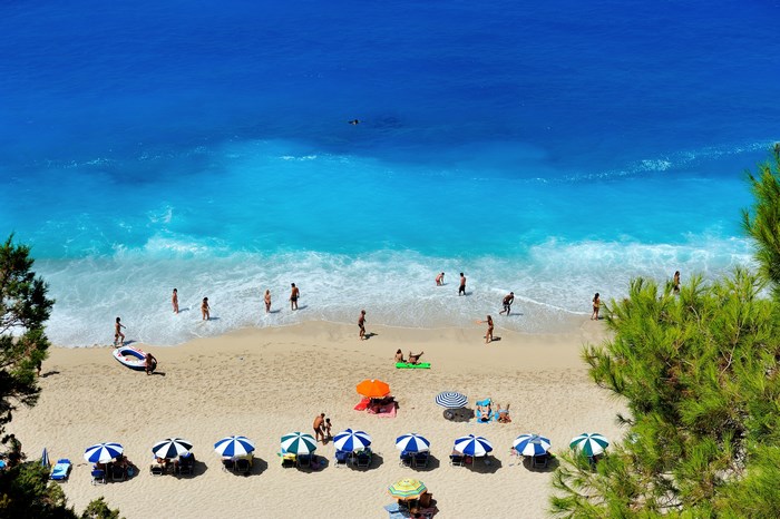 Aerial view of a crowded beach in Greece with turquoise water