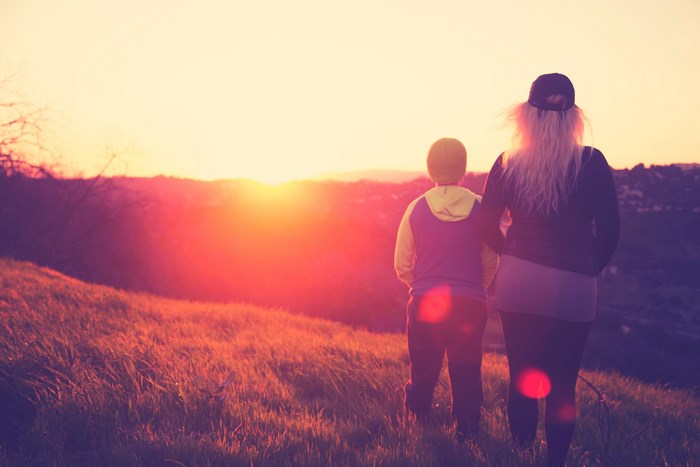 Two people watching the sunset over a hill