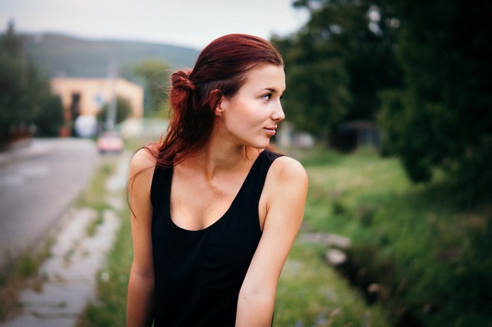 Woman with red hair in a black tank top outdoors