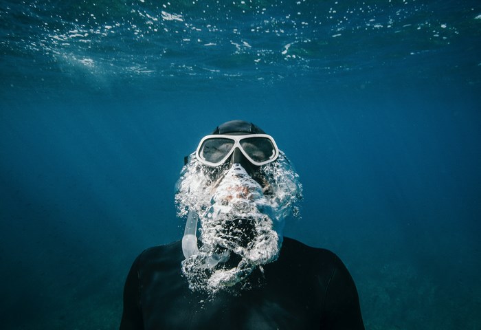 Free diver exhaling bubbles underwater