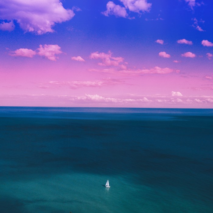Sailboat on the ocean at sunset with purple sky