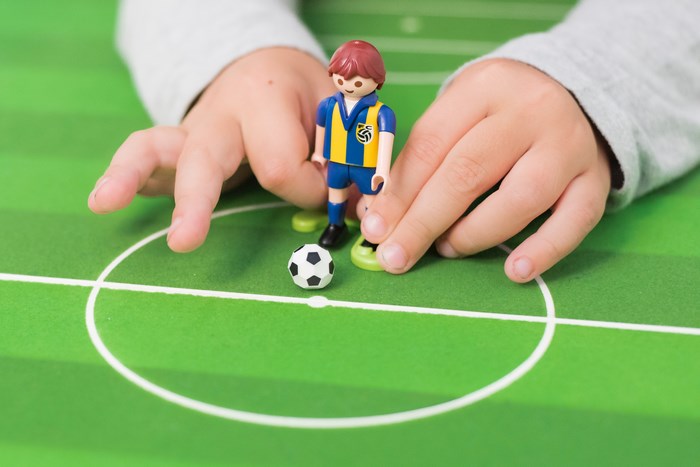 Playmobil soccer player and ball on a field
