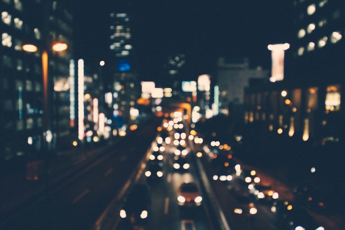 Blurry night cityscape with traffic and illuminated buildings