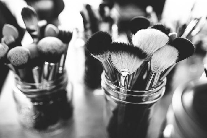 Black and white close-up of makeup brushes in jars
