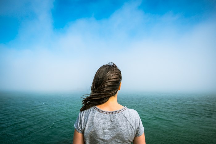 Woman looking out at the foggy ocean