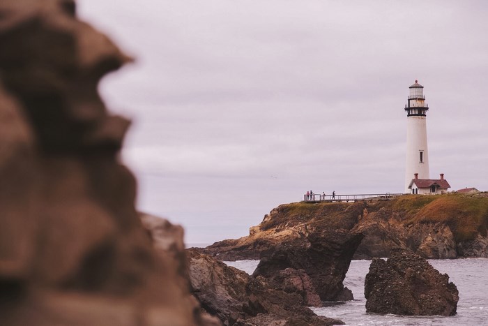 White lighthouse on a rocky coast under a cloudy sky