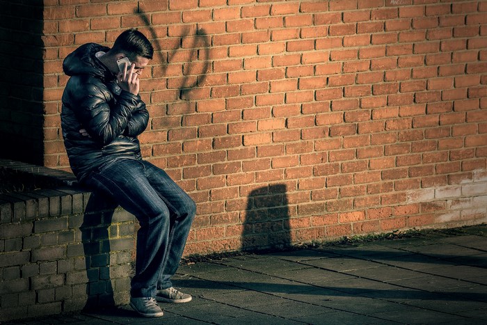 Man sitting on ledge talking on cell phone