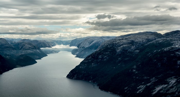 Cloudy sky over a Norwegian fjord with rocky mountains