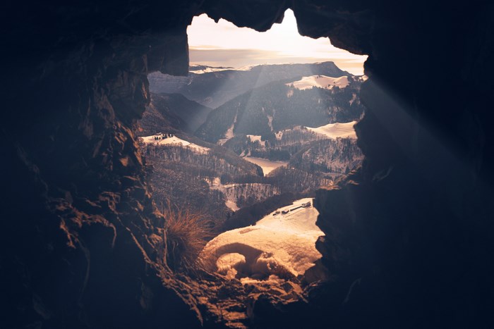 View of snowy mountains from a cave entrance