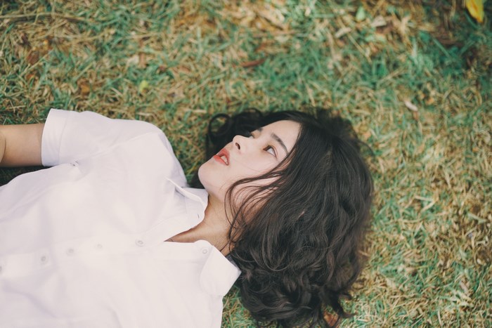 Woman with black curly hair lying on grass