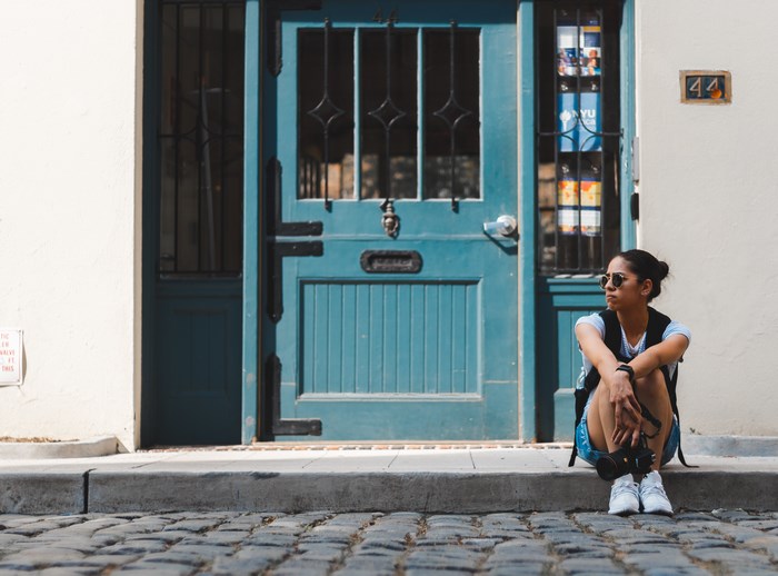Woman sitting by a blue door holding a camera