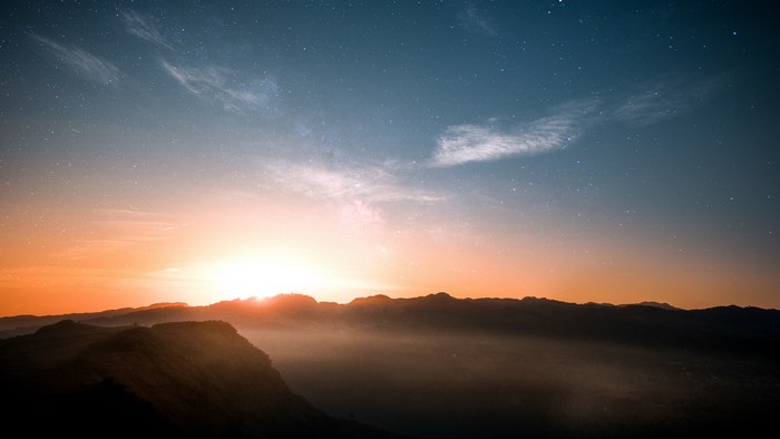Sunrise over misty mountains with stars in the sky