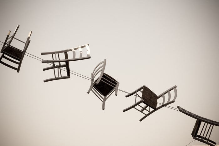 Chairs suspended on cables against a pale sky
