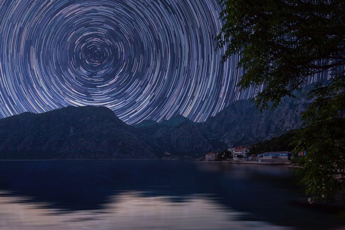 Star trails over mountains and water at night