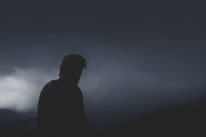 Person in hoodie against dark cloudy sky