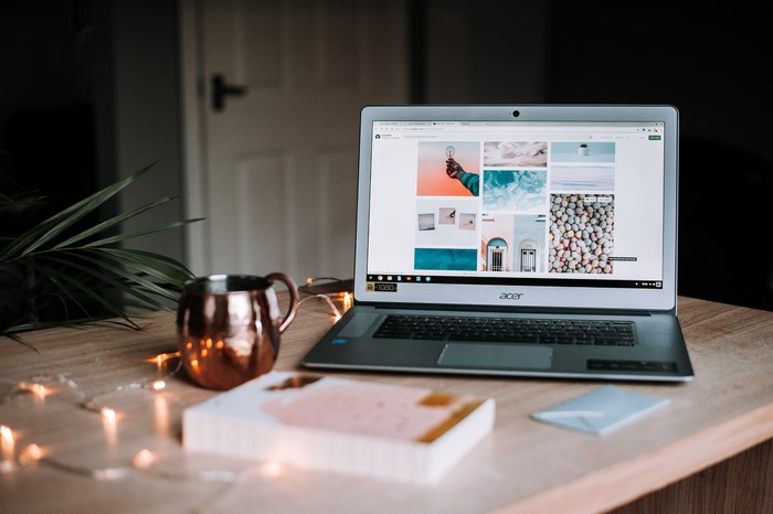 Acer laptop with images on screen, copper mug, and book on table