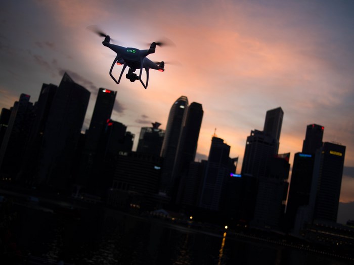 Drone flying over city skyline at sunset