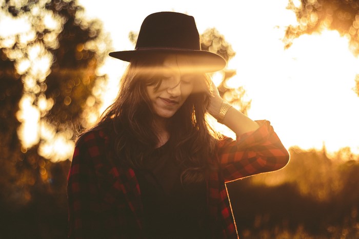 Woman in hat and plaid shirt at sunset