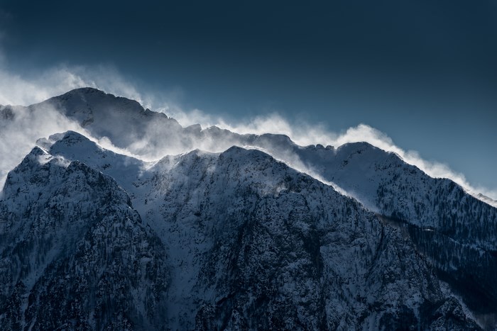 Snowy mountain range with mist and wind