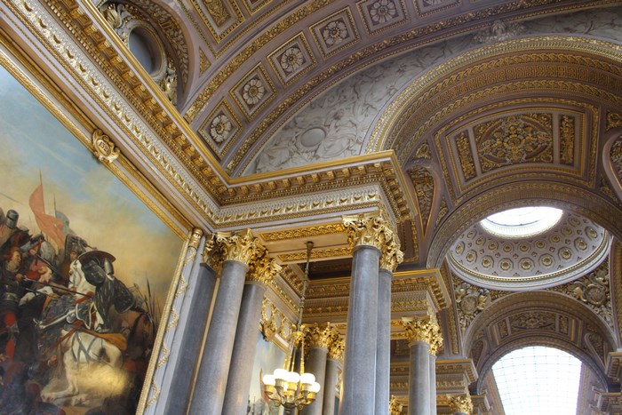 Ornate gold ceiling with painting and columns