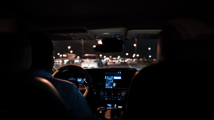 Two people in a car at night with city lights