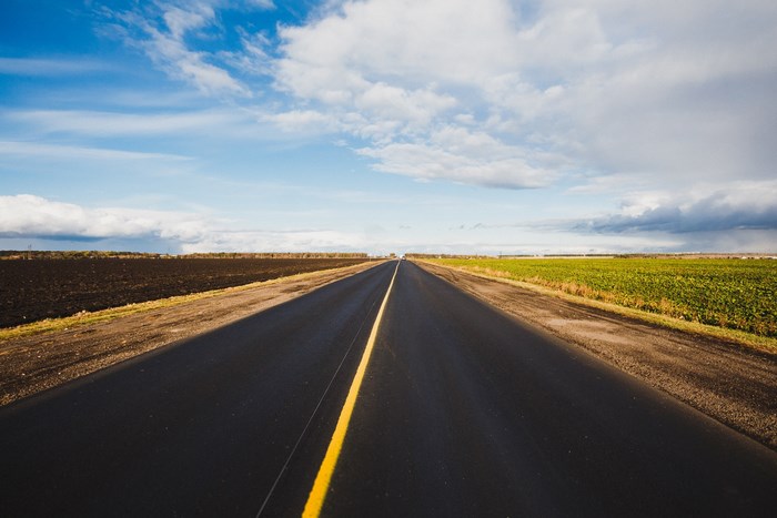 Highway through farmland under a cloudy sky