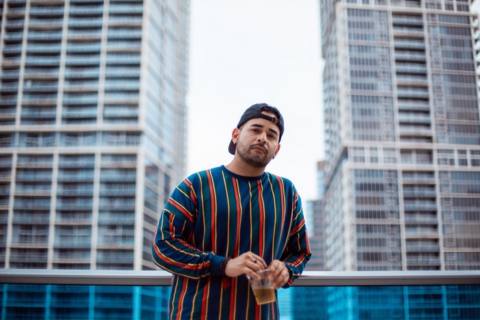 Man in striped shirt holding a drink on a rooftop
