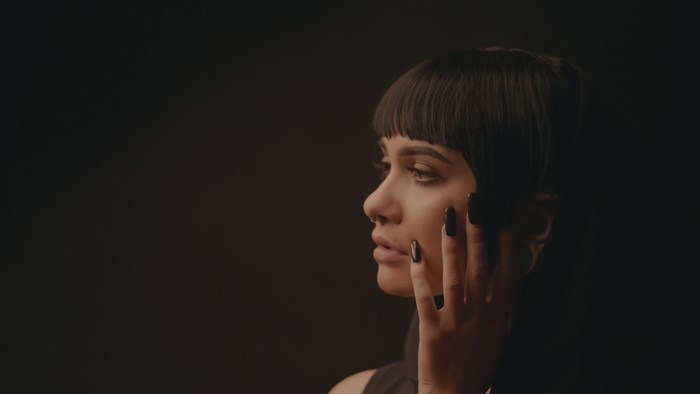 Woman with dark hair and black nails