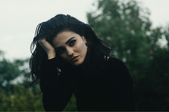 Woman with dark hair in a black top outdoors